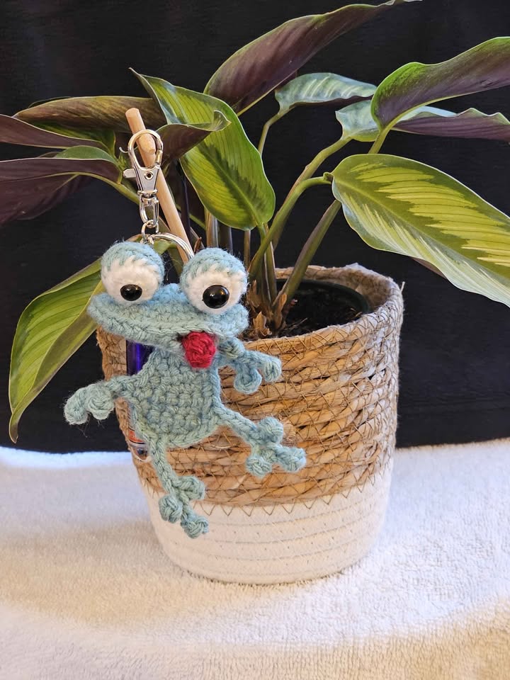 Crochet frog with a small plant in a cozy handmade setup